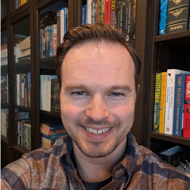 Joe Stech, in front of a bookshelf